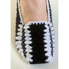 a pair of black and white crocheted slippers on someone's foot