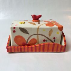 a decorated cake sitting on top of an orange and white striped tray with a red bird