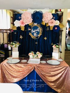 a table topped with cakes and flowers on top of a blue table cloth covered table