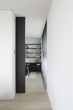 an empty room with white walls and wooden flooring is seen in this image, there are bookshelves on either side of the wall