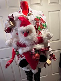 a man dressed up as santa claus holding a teddy bear in his arms with christmas decorations around him