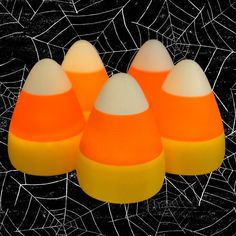 four orange and white candy corn on a black background with spiderwetche web