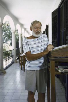 an older man standing in front of a desk