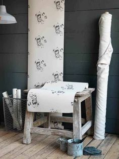 a white chair sitting on top of a wooden floor next to a wall covered in black and white flowers