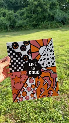 a person holding up a card with the words life is good on it in front of some trees