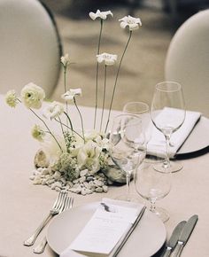 the table is set with white flowers and silverware