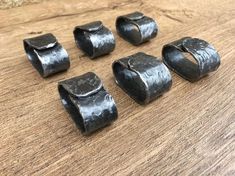 six pieces of black metal sitting on top of a wooden table next to each other