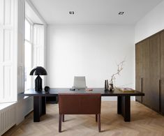 an office with a desk, chair and lamp in the middle of it on top of hard wood flooring