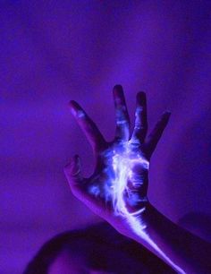 a person's hand is covered in fluorescent light and the fingers are glowing purple