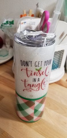 a cup that has some scissors in it on a table next to other items and utensils