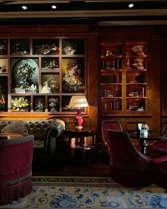 a living room filled with furniture and lots of bookshelves on the wall behind it