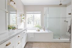 a large bathroom with white cabinets and marble counter tops, along with a walk in shower