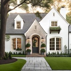 a white house with lots of windows and plants on the front door is pictured in this image