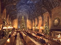 an indoor dining hall decorated for christmas with lit candles and trees in the center, surrounded by snow falling from the ceiling