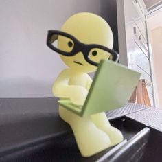 a small toy sitting on top of a desk next to a laptop computer and eyeglasses