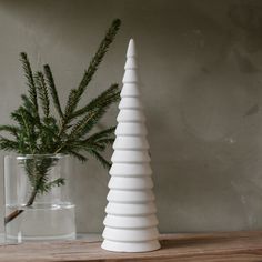 a white christmas tree sitting on top of a wooden table next to a glass vase