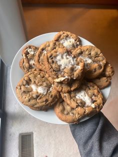 chocolate chip cookies with marshmallows are on a white plate, ready to be eaten