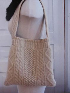 a white knitted handbag sitting on top of a mannequin's head