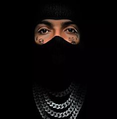 a man wearing a black hat with chains on his face