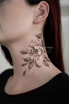 a woman's neck with a flower tattoo on the back of her neck and behind her ear