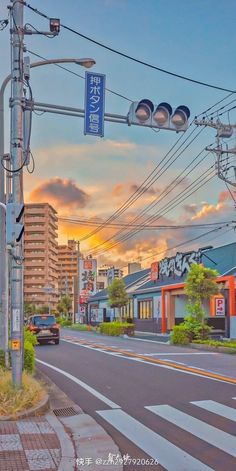 an empty street with traffic lights and buildings in the background at sunset or sunrise time