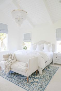 a bedroom with white furniture and blue rugs