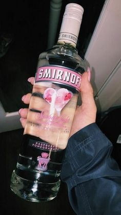 someone holding up a bottle of smirnoff vodka