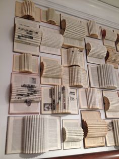 many open books are arranged on the wall above a wooden headboard, with several folded pages attached to it