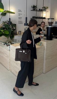 a woman standing in front of a counter holding a brown bag