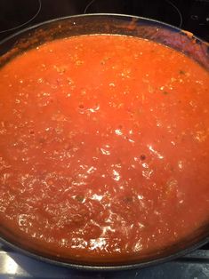 a pan filled with tomato soup sitting on top of an oven