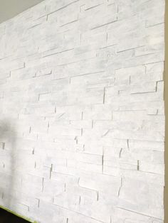 a man standing in front of a white brick wall