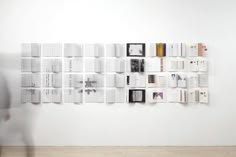 a person standing in front of a white wall with books on it