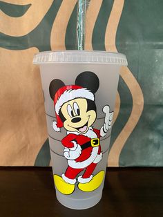 a plastic cup with a mickey mouse design on the side and a straw sticking out of it