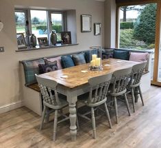 a dining room table with six chairs and a bench in front of the window,