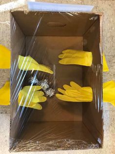 two yellow gloves are placed in a cardboard box