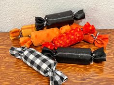 several different types of candy wrapped in black and orange ribbons on a table with a white wall behind it