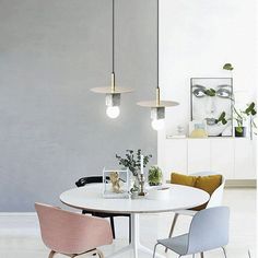 a white table with two chairs and three lights hanging from it's ceiling in a room