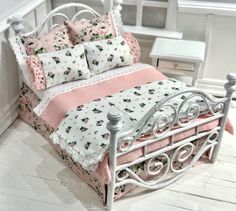 a white metal bed with pink and white bedspread on it's sides