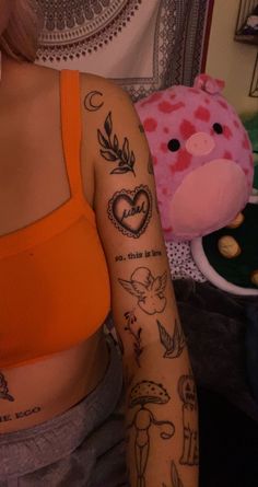 a woman with tattoos on her arm next to a pink teddy bear and other items