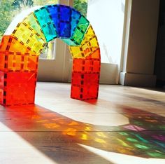 two colorful sculptures sitting on top of a hard wood floor next to a large window