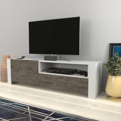 a flat screen tv sitting on top of a wooden entertainment center next to a potted plant