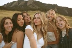 a group of young women standing next to each other in front of a mountain range