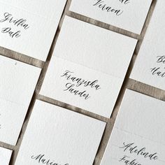 many different types of business cards with black ink and calligraphy on them, all lined up in rows