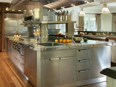 a large kitchen with stainless steel appliances and wooden flooring, along with white walls