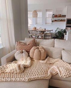 a living room filled with lots of pillows and blankets on top of a couch next to a window