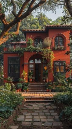 a red house with lots of plants and trees on the front door is surrounded by greenery