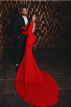 a man in a tuxedo standing next to a woman in a red dress