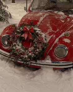 an old red car covered in snow with a wreath on the front