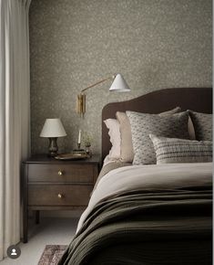 a bed sitting next to a lamp on top of a wooden dresser in a bedroom