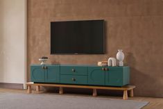 a large flat screen tv mounted to the side of a green cabinet in a living room